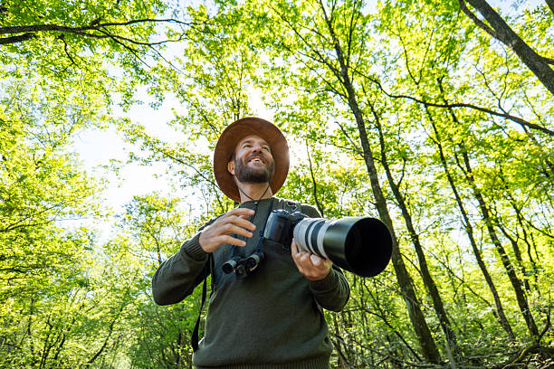 istock Nature Photographer Capturing Wilderness under Sunlit Trees 2211557398