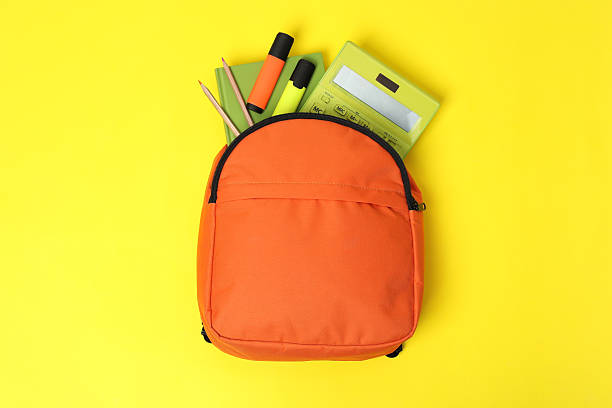 istock Orange backpack with different school supplies on yellow background, top view 2211560958