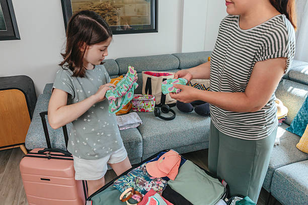 istock Mother and daughter looking bikini for summer holidays while packing suitcase at home 2211561383