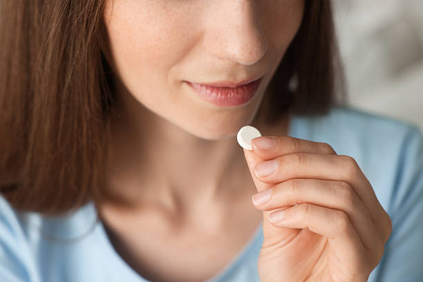 istock Woman taking pill on blurred background, closeup 2211561648