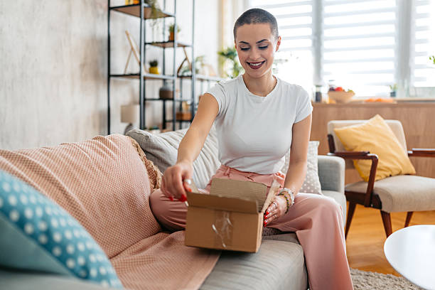 istock Young Woman With A Buzz Cut Unboxing A Package She Ordered Online 2211563449