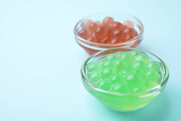 istock Bright tapioca pearls in bowls on light blue background, closeup. Space for text 2211564930