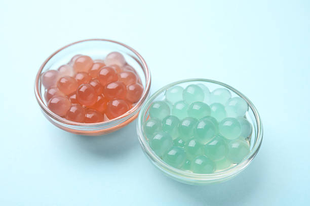 istock Bright tapioca pearls in bowls on light blue background, closeup 2211564948