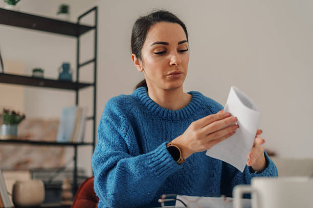 istock Woman opening envelope containing documents at home office desk 2211565406