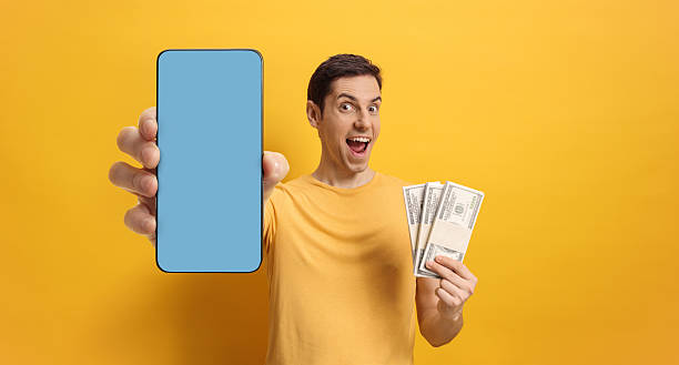 istock Happy young man holding money and smartphone with blue screen 2211565498