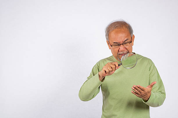 istock Portrait Asian old man with glasses is looking through a magnifying glass studio shot isolated on white background. senior man use magnifier 2211566229