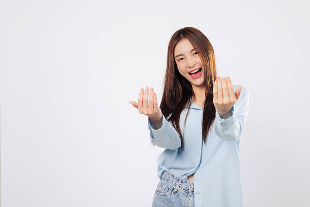 Woman gestures come here with open palm, second woman inviting with cheerful face
