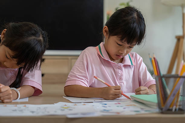 istock Focused Learning and Creativity. Two girls deeply engaged in their coloring projects at home. 2211567597