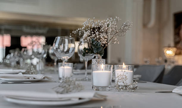 istock beautiful table decoration in restaurant. festive table setting in restaurant. white tablecloth on table, wine glasses, white plates, flowers in vase, candles are burning. romantic atmosphere 2211569109