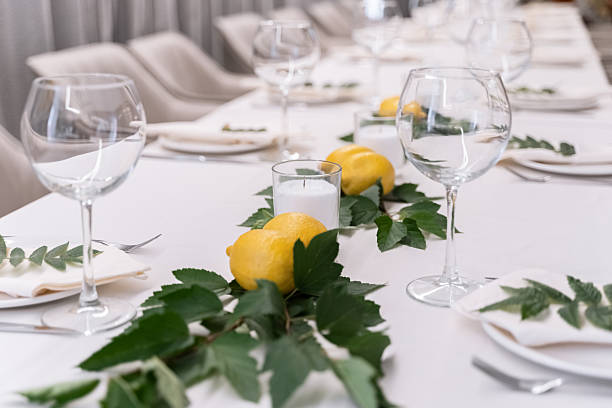 istock beautiful table decoration in restaurant. festive table setting in restaurant. white tablecloth on table, wine glasses, white plates, lemons, candles are burning. romantic atmosphere 2211569117