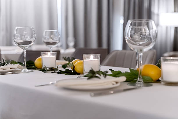 istock beautiful table decoration in restaurant. festive table setting in restaurant. white tablecloth on table, wine glasses, white plates, lemons, candles are burning. romantic atmosphere 2211569130