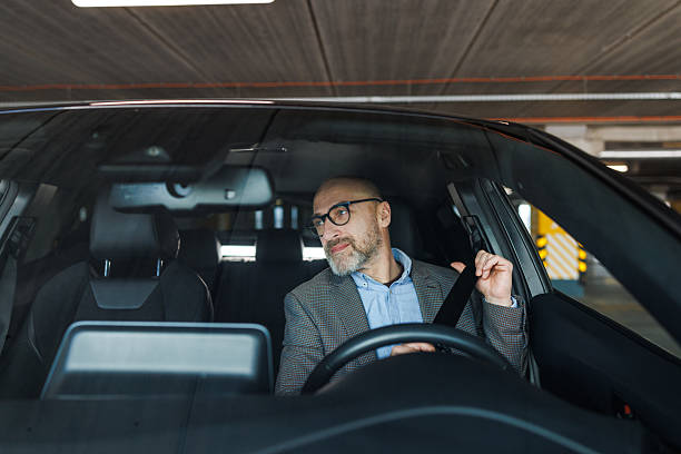 istock Man adjusting seatbelt in a parked car while preparing to drive 2211572543