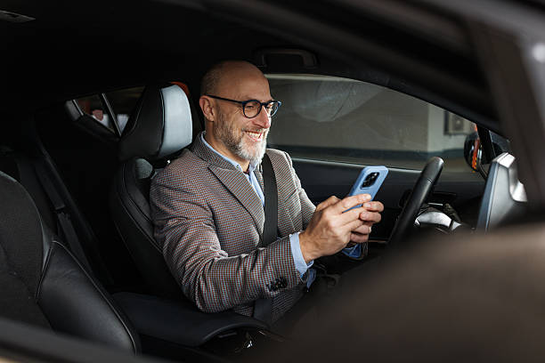 istock Mature businessman using a smartphone while seated in a modern vehicle 2211572609