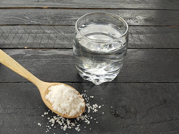istock Salt water solution in glass on black wooden table background 2211573385