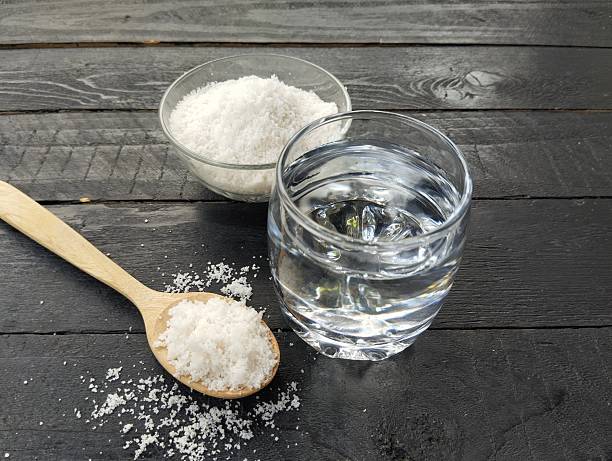 istock Salt water solution in glass on black wooden table background 2211573386