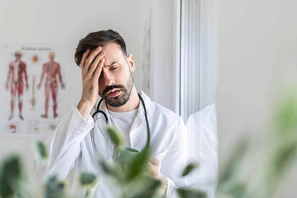 istock Overworked Doctor Experiencing Headache at Office 2211585097