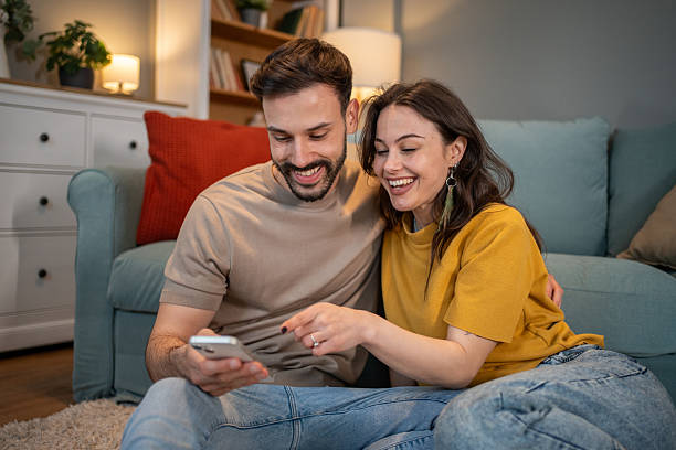 istock Young couple laughing and using smartphone at home 2211588955