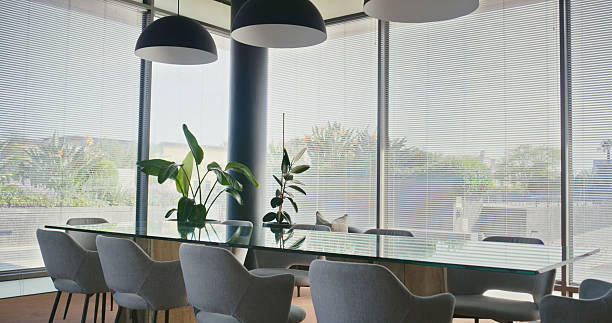 Interior, boardroom and table with chairs for decor, meeting space and windows for modern design. Empty conference room, office and furniture for professional workspace with seminar or workshop setup