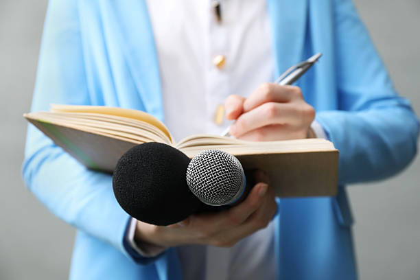istock Journalist with microphones taking notes on grey background, closeup 2211599253