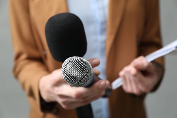 istock Journalist with microphones and notebook on grey background, closeup 2211599264