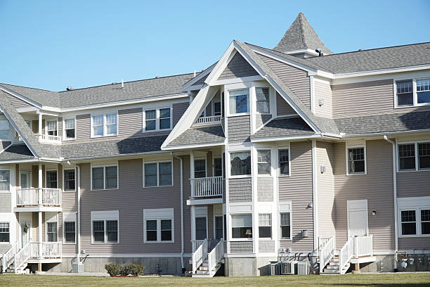modern, multi-story residential buildings with large windows and beige stone facades. The architecture is elegant and contemporary. The weather is clear and sunny, with a bright blue sky