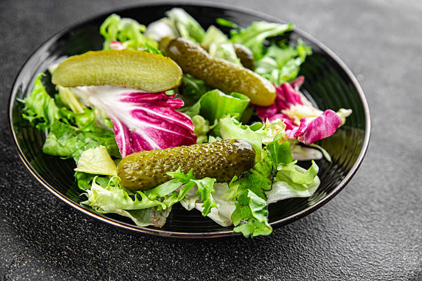 Pickle salad gherkins pickled cucumbers mixed green leaf lettuce appetizer vegetables dish organic fresh tasty gourmet food background on the table food top view copy space vegetarian vegan food