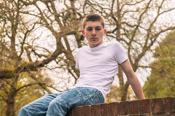 istock Teenage boy sitting on a brick wall 2211607031