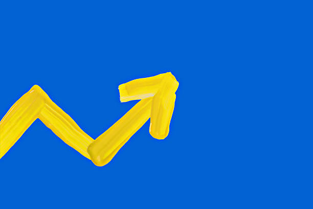 Bold upward arrow made with yellow paint brushstrokes on solid blue background. Represents economic growth, success, development, improvement, progress and upward business trends