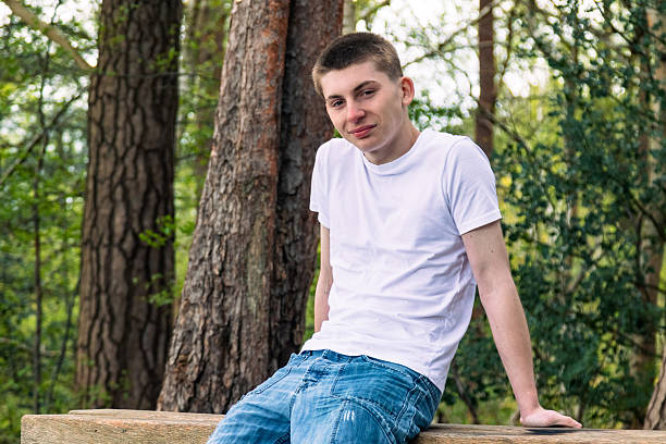 istock Teenage boy sitting on a park bench 2211610593