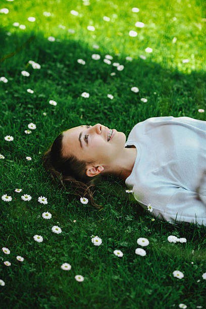 Joyful Girl Gazing Clouds in Sky While Lying on Grass With Flowers