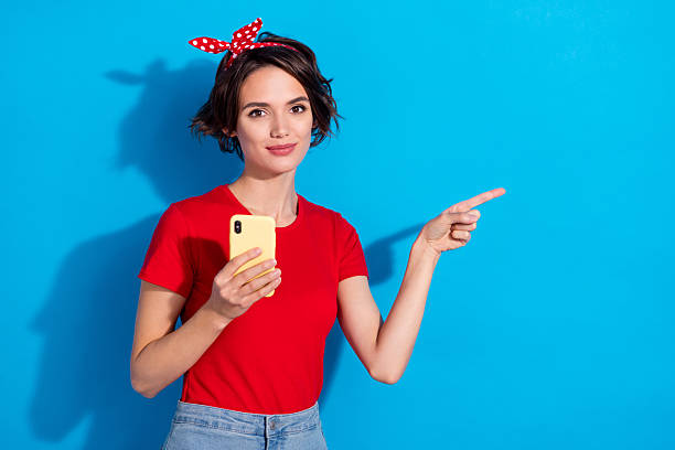 istock Photo of young lady indicate finger empty space ads recommend suggest app subscribe isolated over blue color background 2211611925