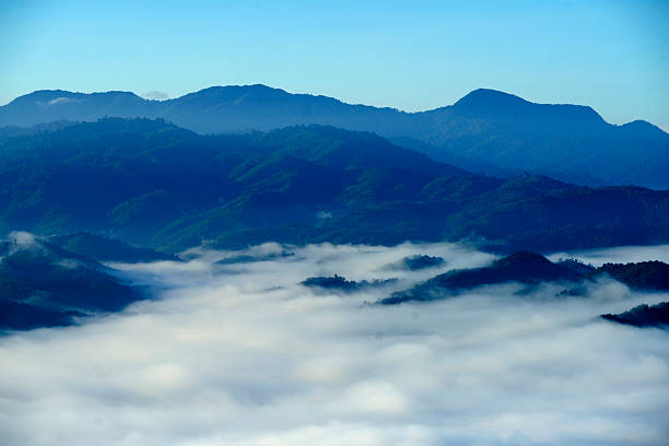 A stunning view of misty clouds blanketing rolling mountains at dawn, showcasing nature's serene beauty and tranquility in a peaceful landscape.