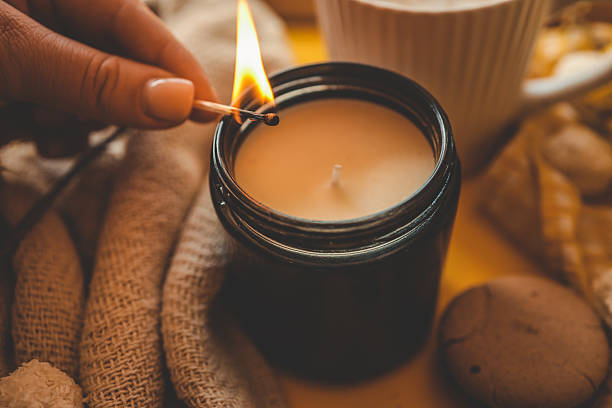 istock A cozy spring flat lay with a hand lighting a candle, a cup of coffee, a soft blanket, yellow flowers, an open book, and sweet treats on a bright yellow background, creating a peaceful mood 2211621201