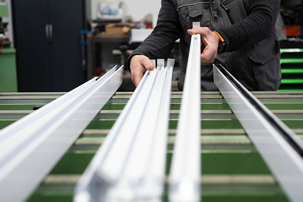 Carpenter carefully inspecting aluminum profiles, ensuring quality and precision in a bustling workshop environment
