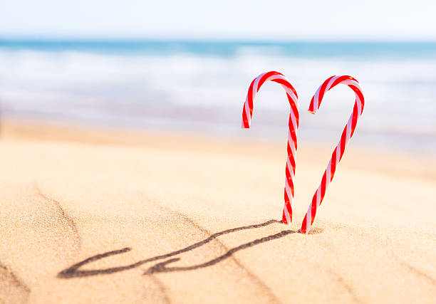 Candy canes in the sand of an idyllic, warm beach in the run up to Christmas.