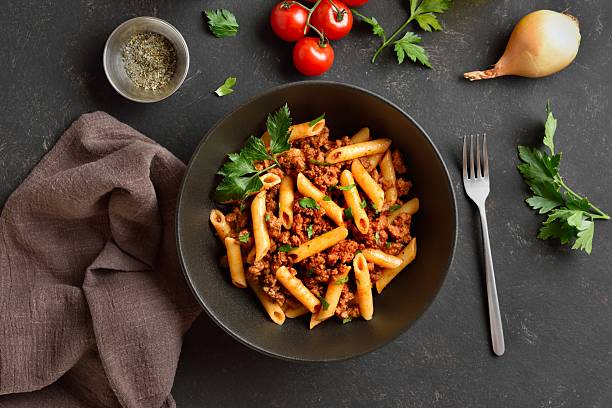 istock Penne pasta with minced meat, tomato sauce and greens 2211622621