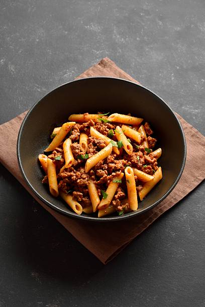 istock Penne pasta with minced meat, tomato sauce and greens 2211622639