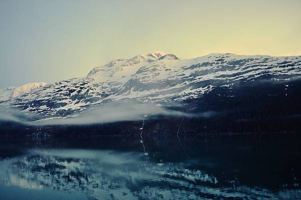 Sailing into Whittier, Alaska via the Passage Canal with the mist hanging over the water and the Chugach Mountains in the background, Cascades of snow melt trickle down the mountainside, a definite sign spring has arrived.