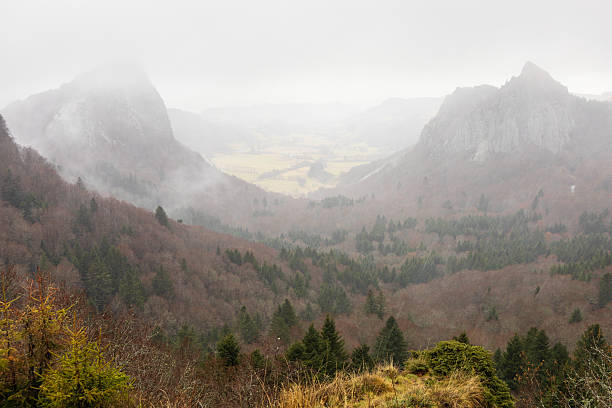 Tuilière and Sanadoire rocky peaks. Clouds, heavy rain. Massif Central, France. Two rocky peaks, Tuilière and Sanadoire, are the remains of two volcanoes forming the Sancy-Monts Dore complex, separated by a valley. Clouds and heavy rain. Orcival, Massif Central, France. orcival stock pictures, royalty-free photos & images