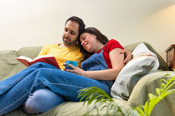 istock Young couple relaxing on sofa, reading and enjoying a quiet moment together 2211632707