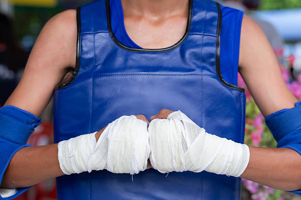 Boxing fighter wrapped fists blue gloves strength focus training combat athlete uniform resilience power challenge determination grit. Handwraps sportswear protection readiness brawler confidence.