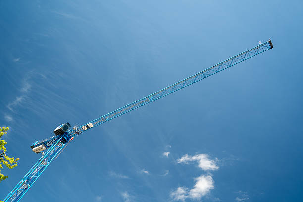 A large blue crane is soaring high in the clear blue sky. The crane is a prominent feature in the image, towering over the vast expanse of the sky