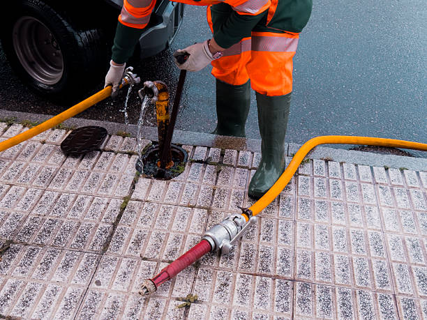 istock Worker in protective gear using hose for street drainage maintenance 2211640826