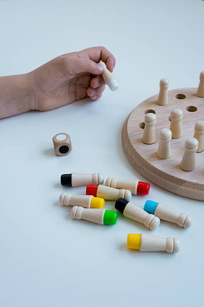 istock Child playing with wooden peg game and dice on white table 2211640947