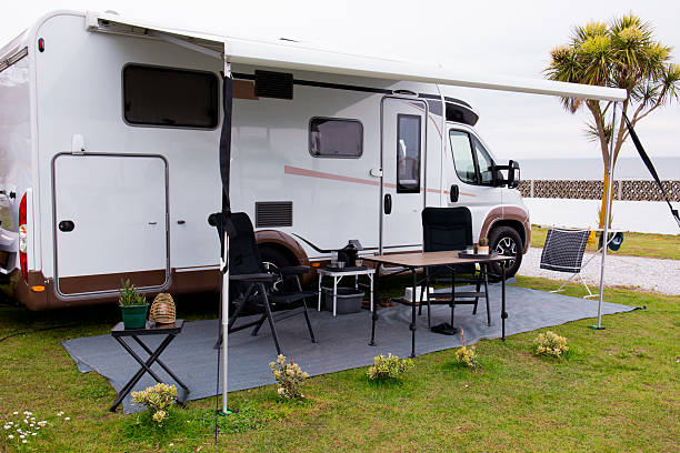 Modern rv camper setup with retractable awning at coastal campsite.