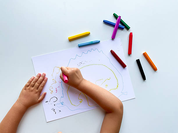 istock Child creating colorful crayon drawing on white paper with vibrant sticks 2211642079