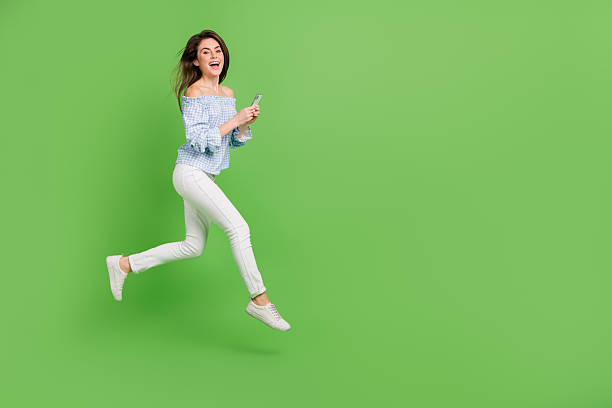 istock Photo of impressed lady dressed blue checkered blouse jumping running reading device empty space isolated green color background 2211646465