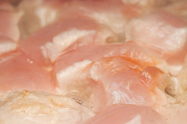 Raw chicken breasts are arranged in a pan.
