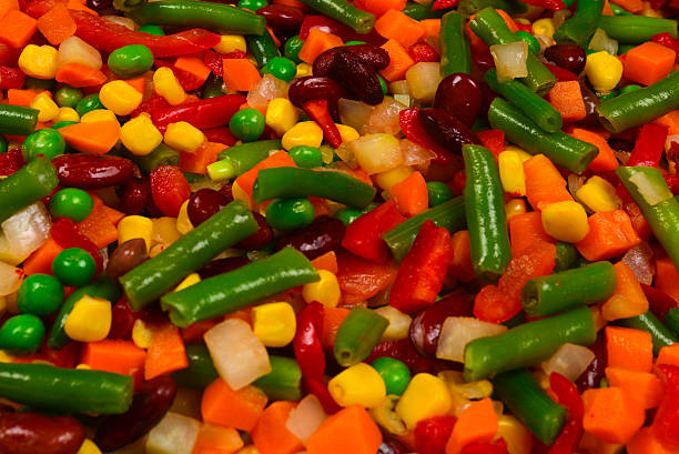 Sliced vegetables, corn, beans, peas, carrots, sweet peppers background.