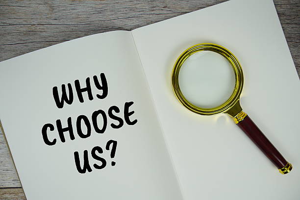 istock Why choose us? text on notebook page with magnifying glass top view on wooden background 2211649416